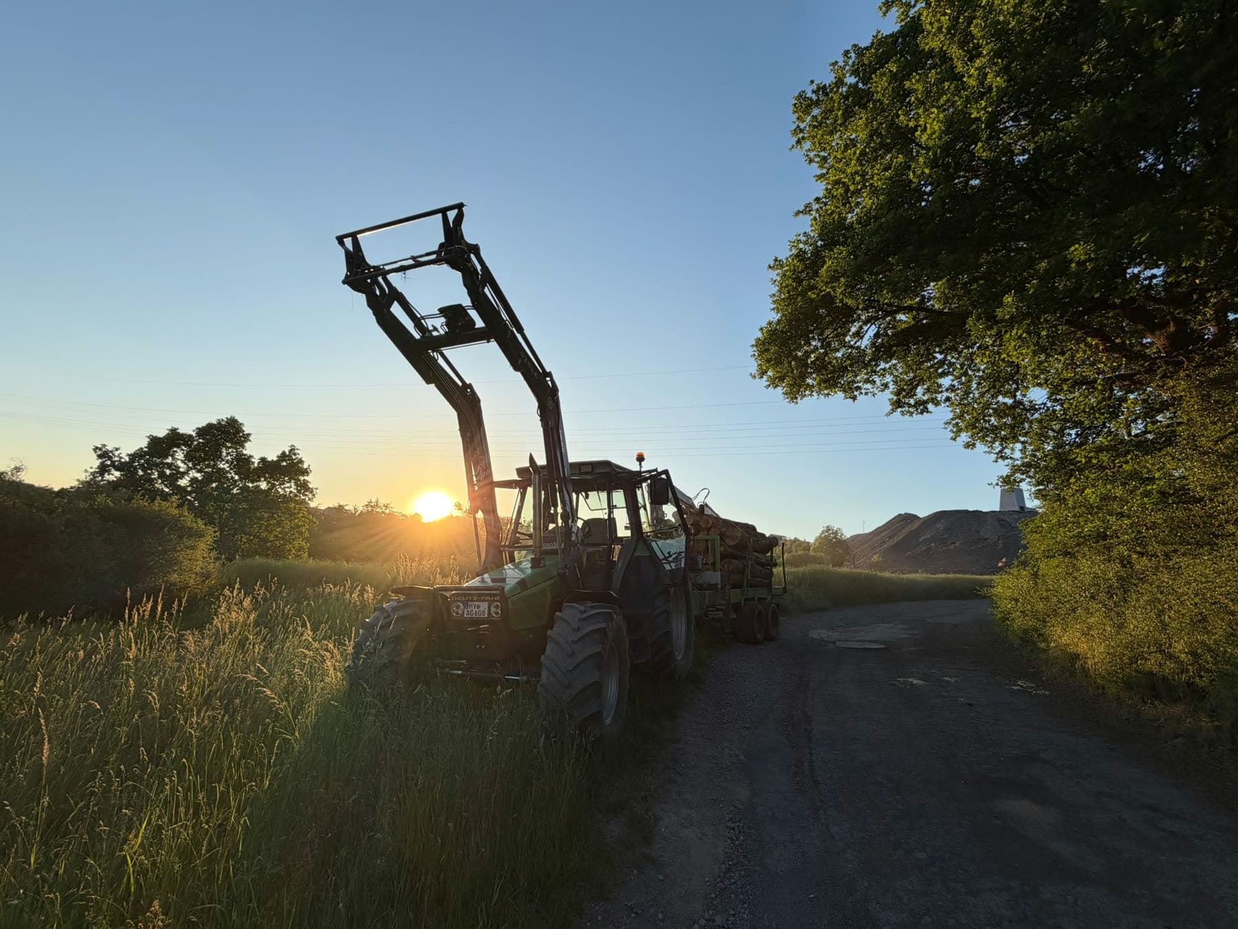 Traktor mit Holzanhänger auf dem Wirtschaftsweg